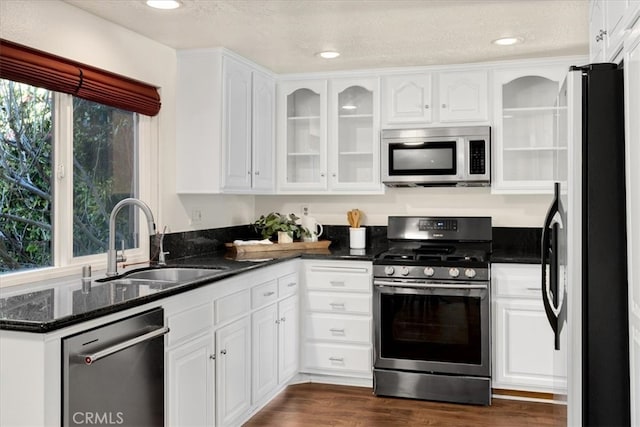 kitchen with a sink, stainless steel appliances, dark wood-type flooring, and white cabinetry