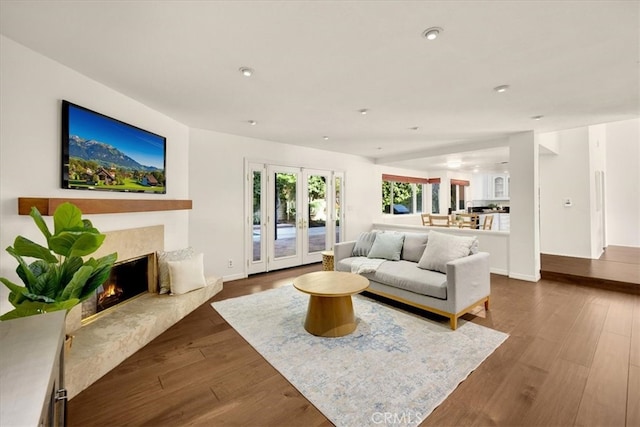 living room with dark wood finished floors, recessed lighting, french doors, a premium fireplace, and baseboards