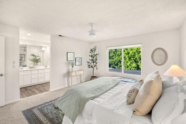 bedroom featuring ensuite bath, visible vents, baseboards, and light carpet