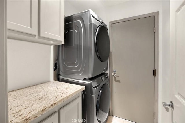 washroom with cabinet space and stacked washer and dryer