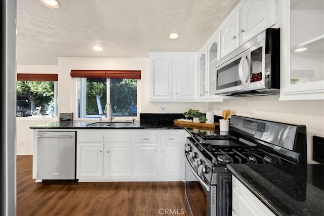 kitchen with a sink, stainless steel appliances, dark wood-type flooring, white cabinets, and glass insert cabinets