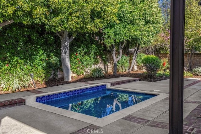 view of swimming pool featuring a swimming pool, a patio, and fence