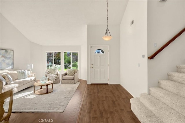 living room with dark wood finished floors, lofted ceiling, stairway, and visible vents