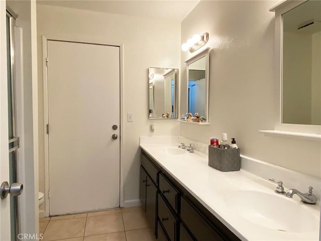 bathroom with double vanity, a sink, toilet, and tile patterned floors