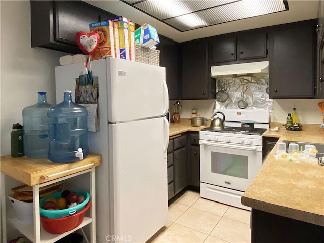 kitchen featuring light countertops, white appliances, light tile patterned flooring, and under cabinet range hood