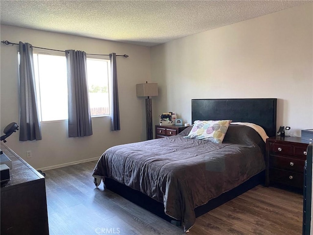 bedroom featuring a textured ceiling, wood finished floors, and baseboards