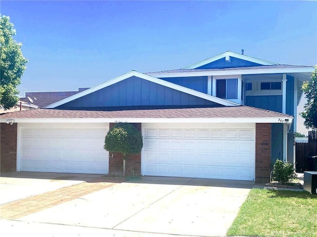 view of front of property featuring driveway, roof with shingles, and brick siding