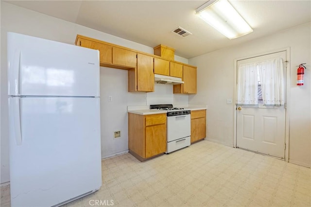 kitchen with white appliances, under cabinet range hood, visible vents, and light floors