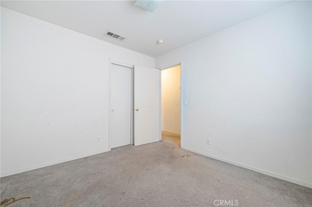 carpeted empty room featuring baseboards and visible vents