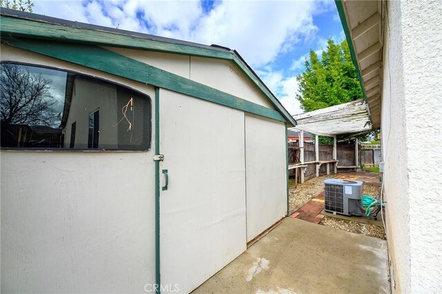 view of property exterior featuring central AC, an outdoor structure, fence, and stucco siding