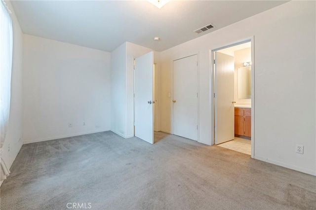 unfurnished bedroom with visible vents, connected bathroom, and light colored carpet