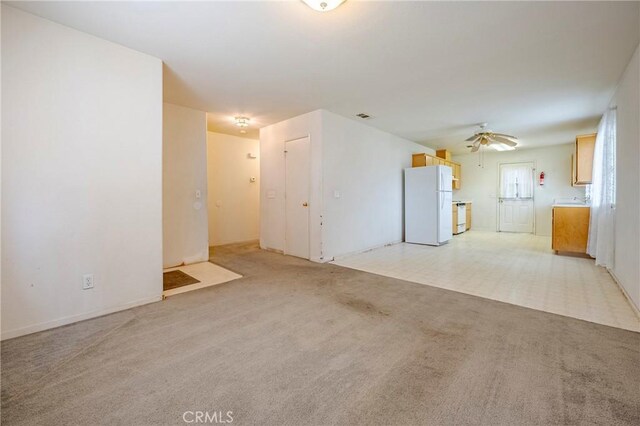 unfurnished living room featuring a ceiling fan, light colored carpet, and visible vents