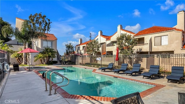community pool with fence and a patio