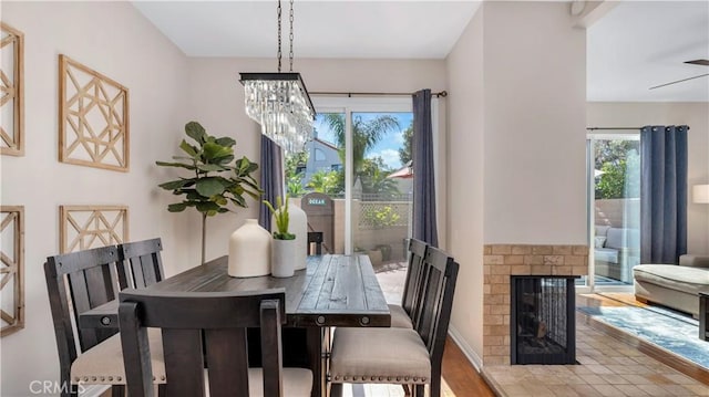 dining area with a chandelier, wood finished floors, and a fireplace