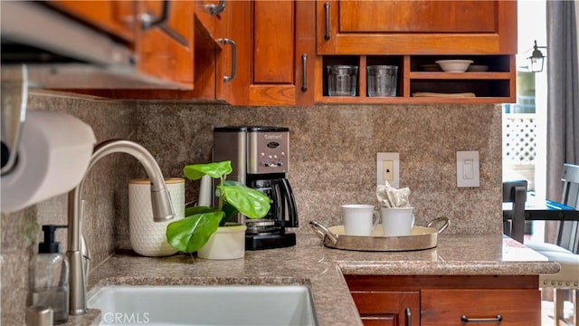 details with open shelves, tasteful backsplash, brown cabinetry, and a sink