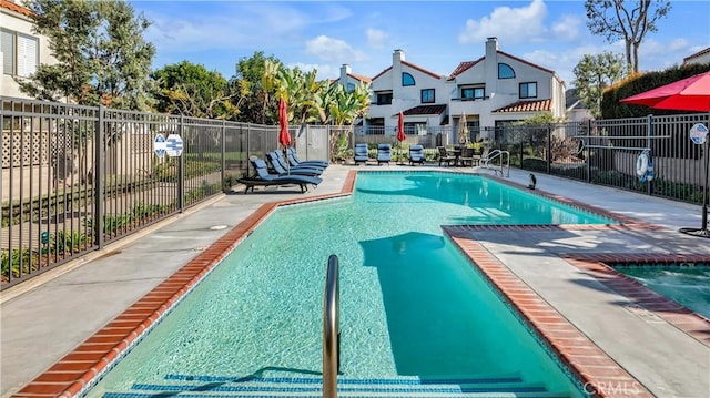 community pool with a residential view, a patio area, and fence
