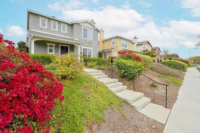 view of front of house with stairs, a residential view, and stucco siding