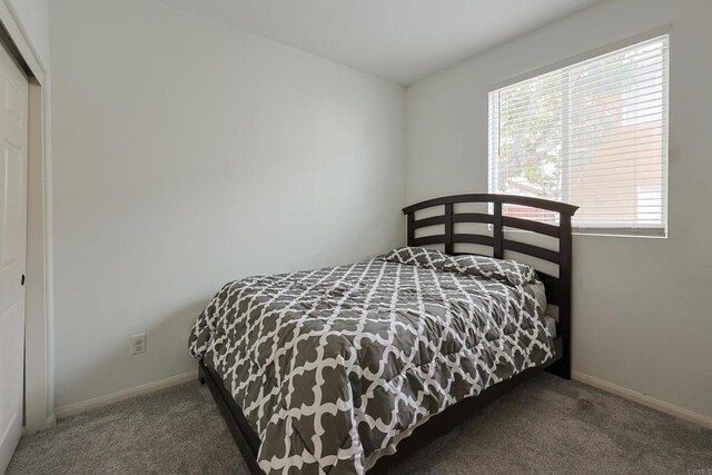carpeted bedroom with a closet and baseboards