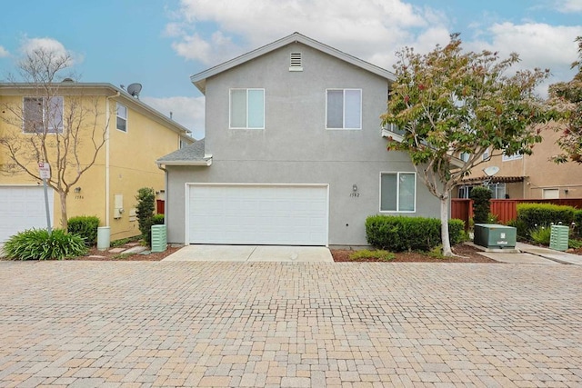 view of front facade with cooling unit, stucco siding, decorative driveway, fence, and an attached garage