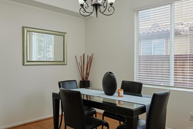 dining area featuring wood finished floors, a notable chandelier, and baseboards
