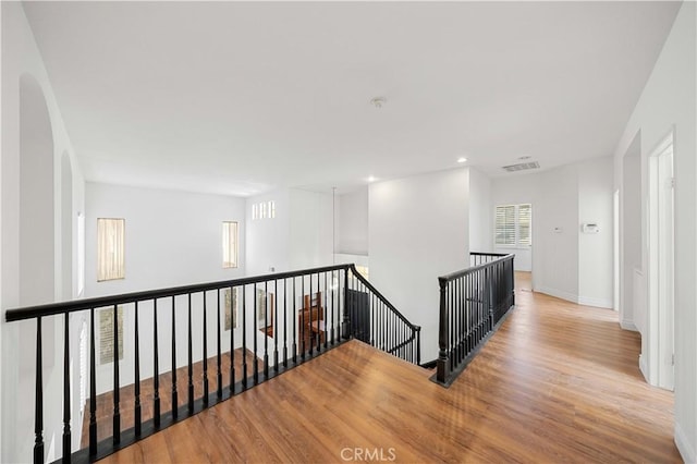 hall featuring baseboards, visible vents, wood finished floors, an upstairs landing, and recessed lighting