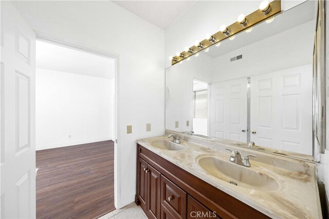 full bath featuring wood finished floors, visible vents, a sink, and double vanity