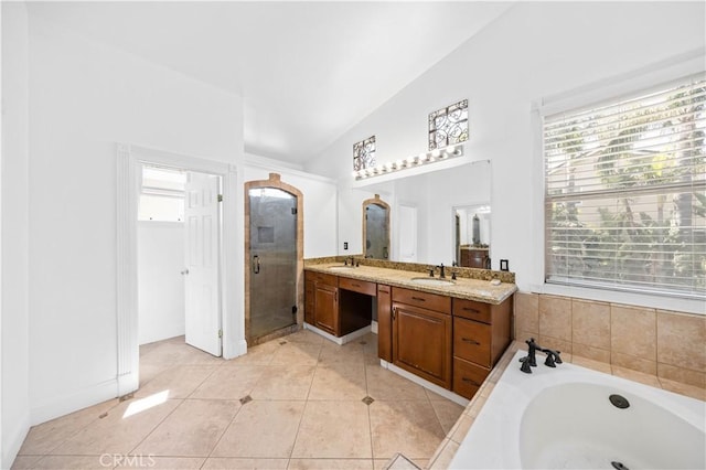 full bath featuring a stall shower, vaulted ceiling, tile patterned flooring, and a sink