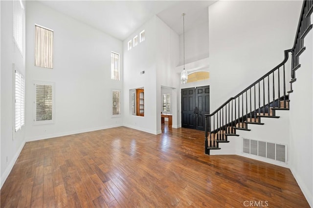 foyer featuring hardwood / wood-style flooring, baseboards, stairway, and visible vents