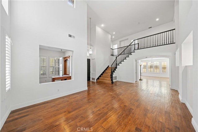 unfurnished living room featuring stairs, a wealth of natural light, hardwood / wood-style flooring, and visible vents