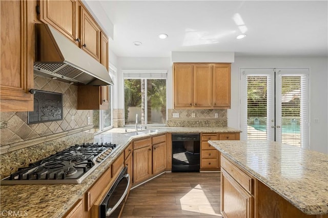 kitchen featuring dark wood finished floors, stainless steel gas cooktop, a sink, dishwasher, and under cabinet range hood