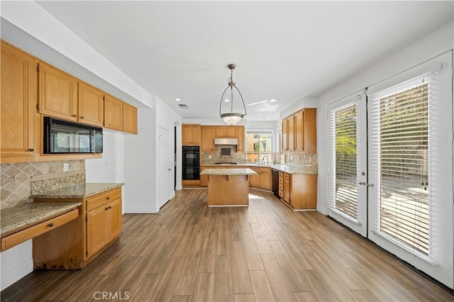 kitchen with light countertops, under cabinet range hood, black appliances, and wood finished floors