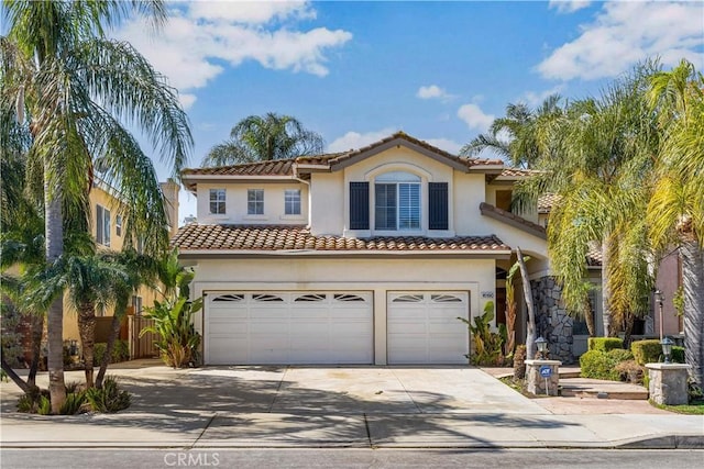 mediterranean / spanish-style home with an attached garage, fence, concrete driveway, a tiled roof, and stucco siding