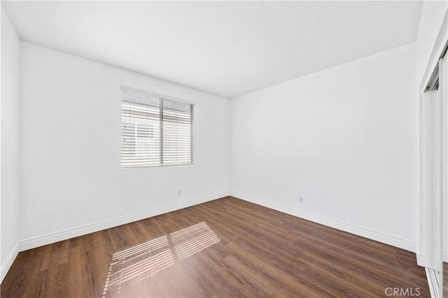 empty room with baseboards and dark wood finished floors