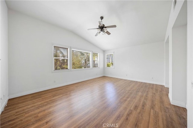 spare room with vaulted ceiling, ceiling fan, wood finished floors, and baseboards