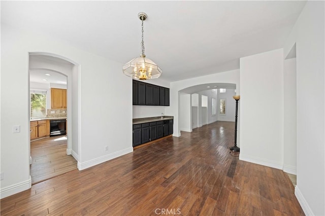 interior space featuring arched walkways, hardwood / wood-style floors, and baseboards