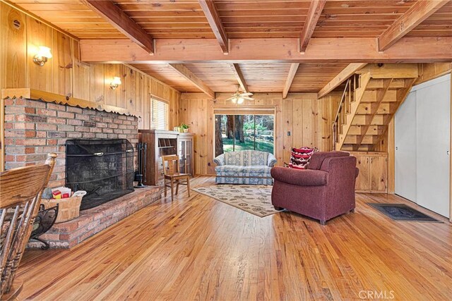 living room with wood ceiling, beamed ceiling, light wood-type flooring, wood walls, and a fireplace