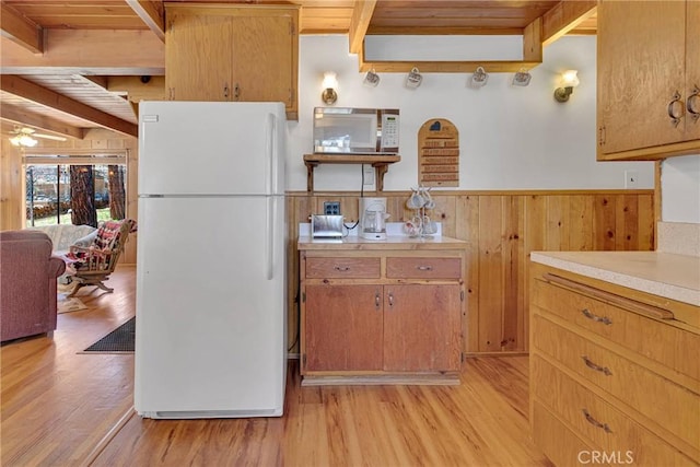 kitchen featuring freestanding refrigerator, beam ceiling, light countertops, and light wood-style flooring