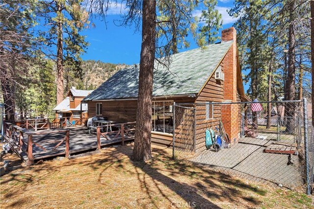 back of house with a chimney and a wooden deck