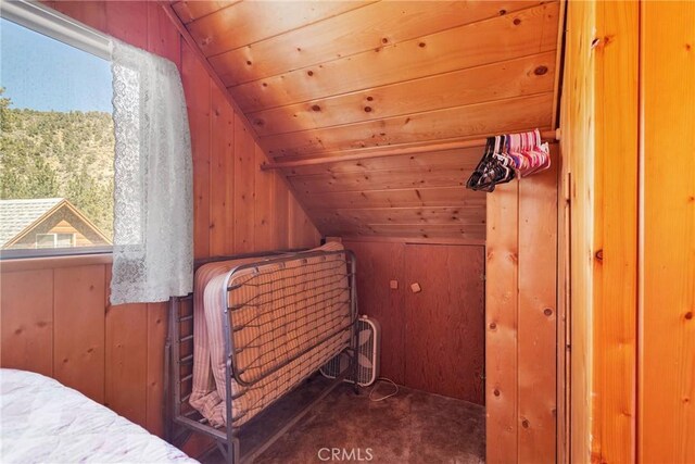 bedroom with wooden ceiling, carpet, wooden walls, and vaulted ceiling