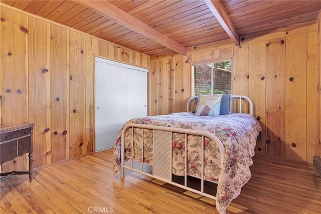 bedroom with wood ceiling, beamed ceiling, wood walls, and wood finished floors