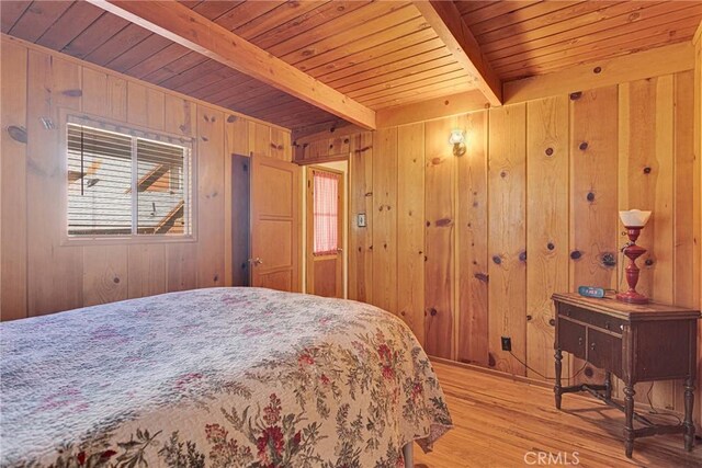 bedroom with light wood finished floors, beamed ceiling, wood ceiling, and wooden walls