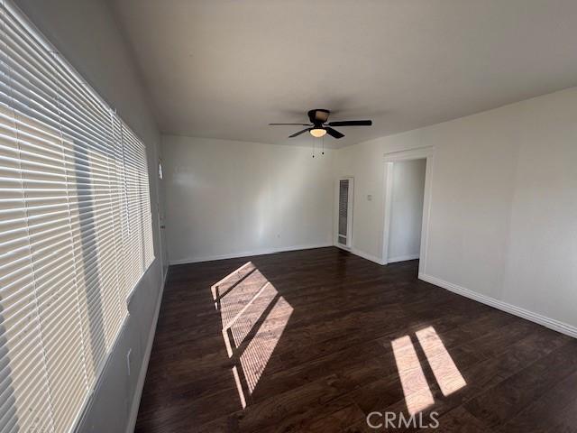 empty room featuring dark wood-style floors, ceiling fan, and baseboards