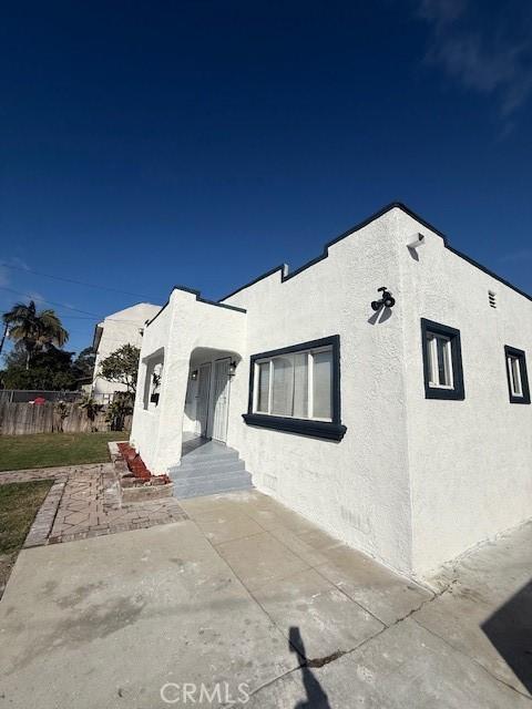 view of front facade featuring a patio area, fence, and stucco siding