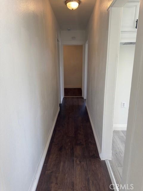 corridor with baseboards and wood finished floors