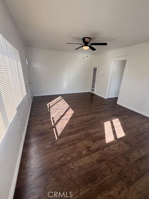 unfurnished room featuring dark wood-style floors, ceiling fan, and baseboards