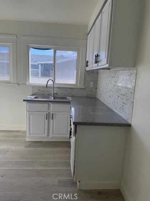 kitchen with light wood-type flooring, tasteful backsplash, and a sink