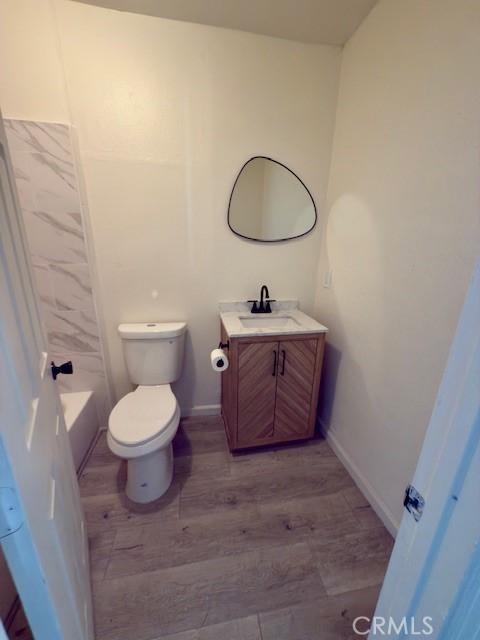 bathroom with toilet, baseboards, wood finished floors, and vanity