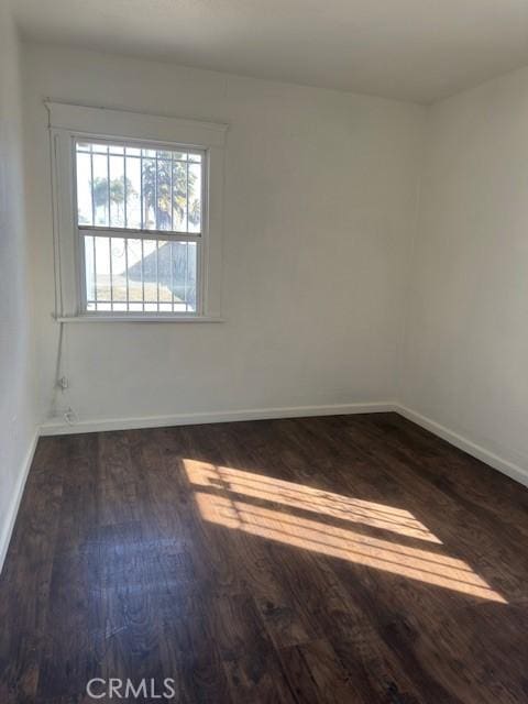 unfurnished room with dark wood-style floors and baseboards