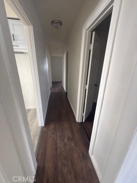 corridor with baseboards and wood finished floors