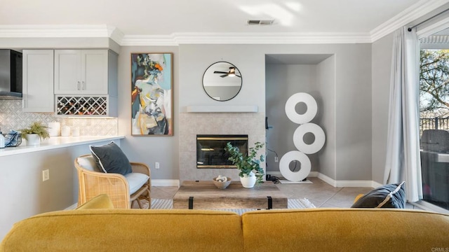 living room featuring light tile patterned flooring, a fireplace, visible vents, baseboards, and ornamental molding